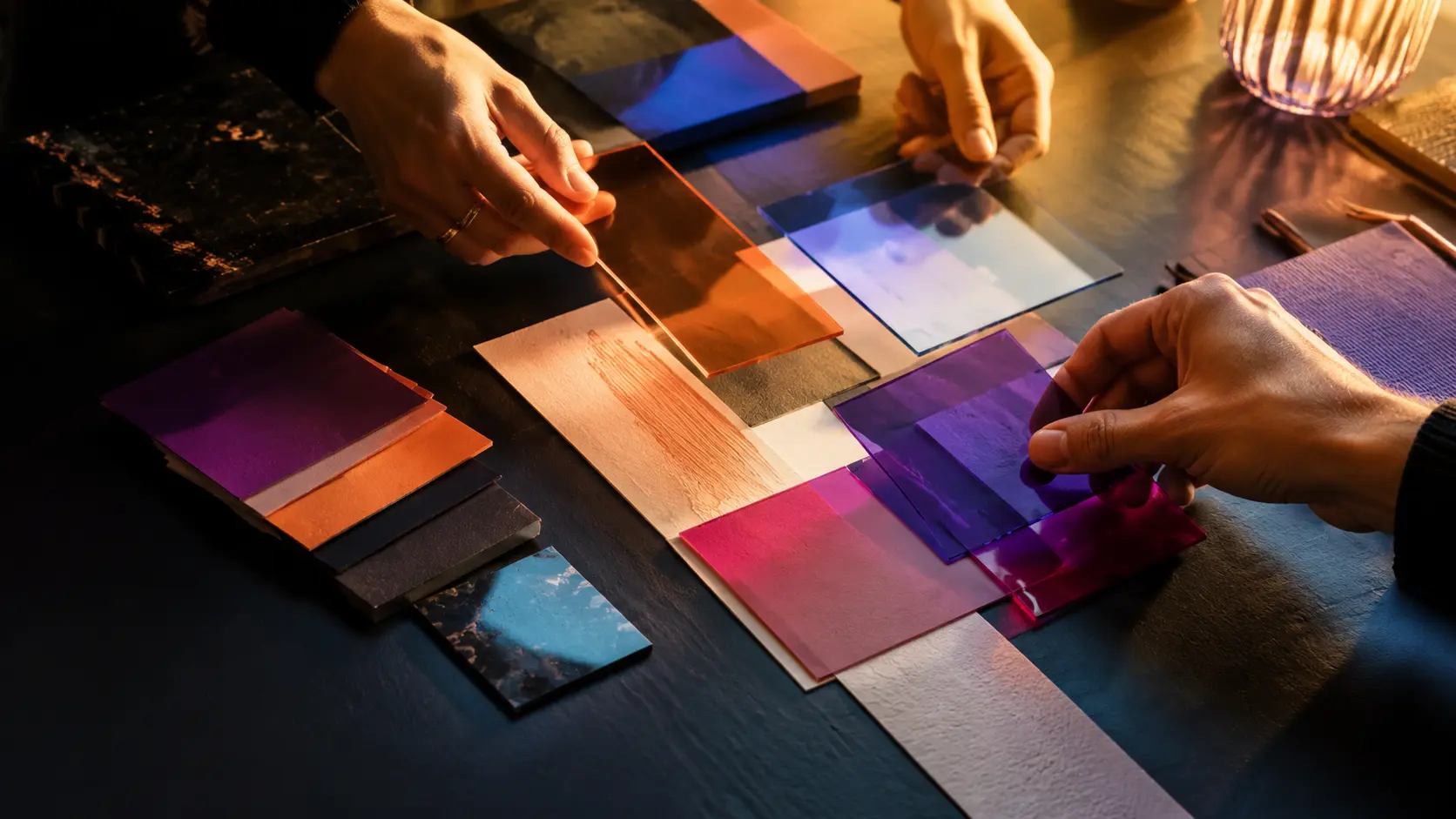 Des mains composent une direction créative avec des matières, des couleurs et des transparences